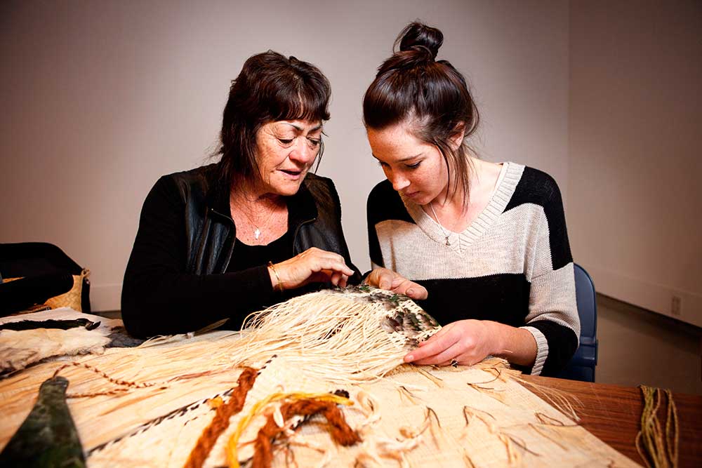 Two women doing Maori weaving 